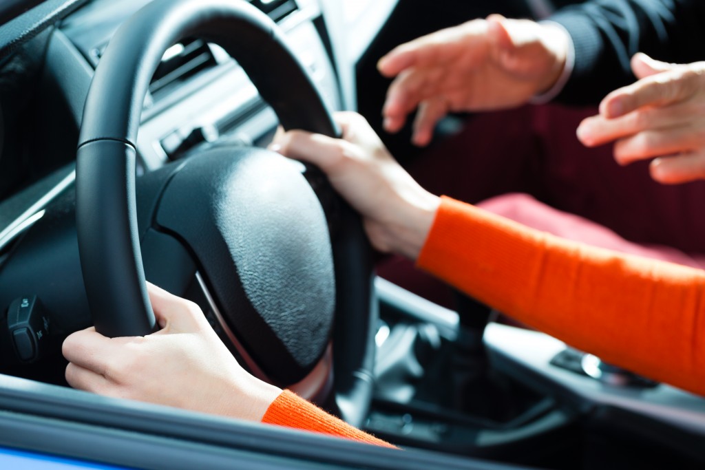 person steering the wheel while another guides them