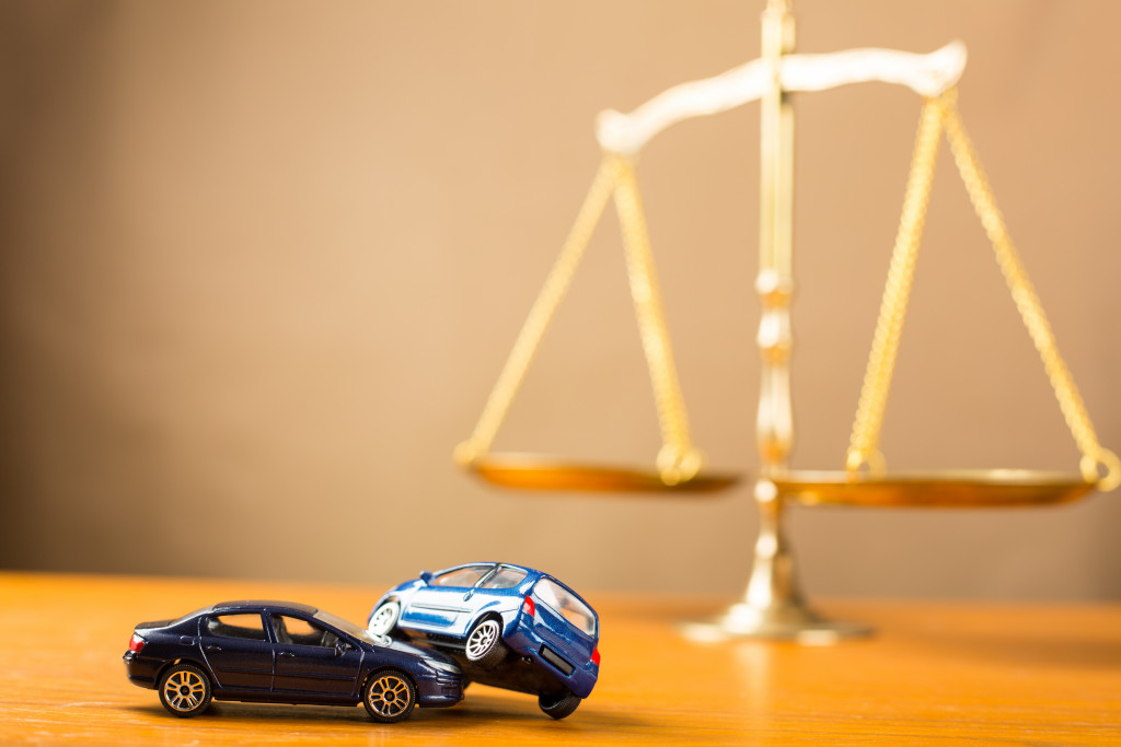 Toy cars in a crash in front of golden scales