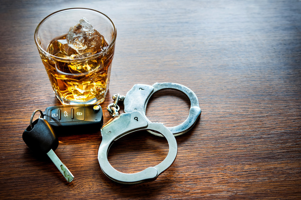 A glass of alcohol, car keys, and hand cuffs