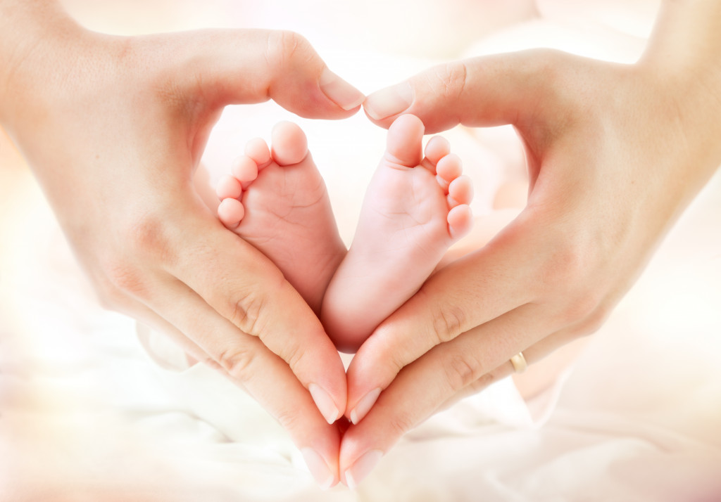 A mother's hand forming a heart around baby's feet