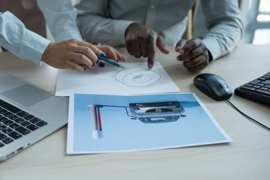 two men in business attire collaborating over a design printout on a desk