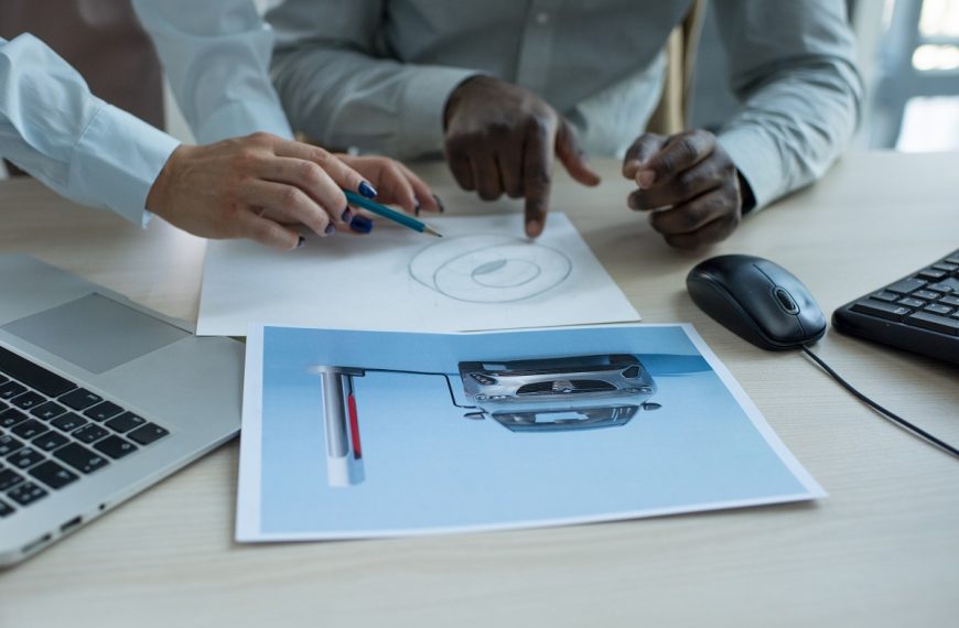 two men in business attire collaborating over a design printout on a desk